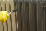 Das Bild zeigt eine Heizung die mit einem Pinsel gestrichen wird.
