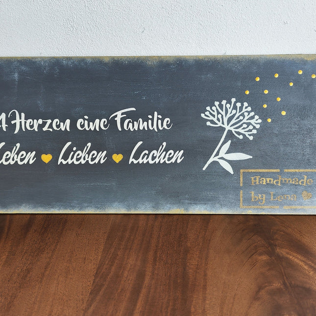 Ein Schild aus unserem Workshop in schwarz mit weißer Schrift, 4 Herzen eine Familie.