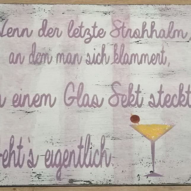 Ein Schild im Shabby-Chic Look mit angedeuteten rosa Streifen und dem Spruch wenn der letzet Strohhalm, an den man sich klammert in einem Glas Sekt steckt, geht´s eigentlich.