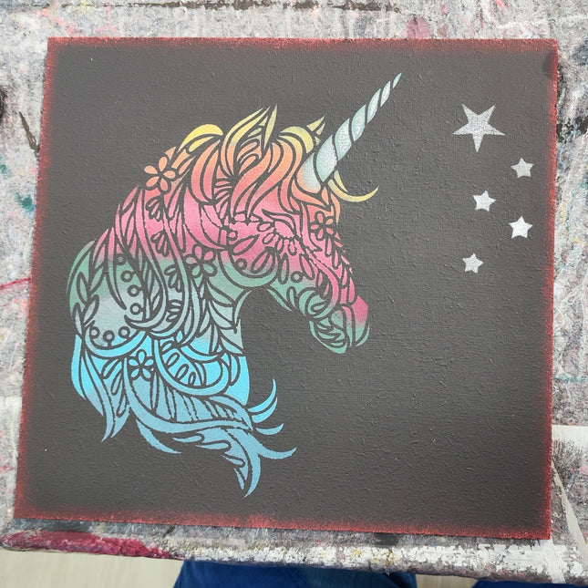 Ein schwarzes Schild mit einem Einhorn in Regenbogenfarben aus unserem Schilder Workshop