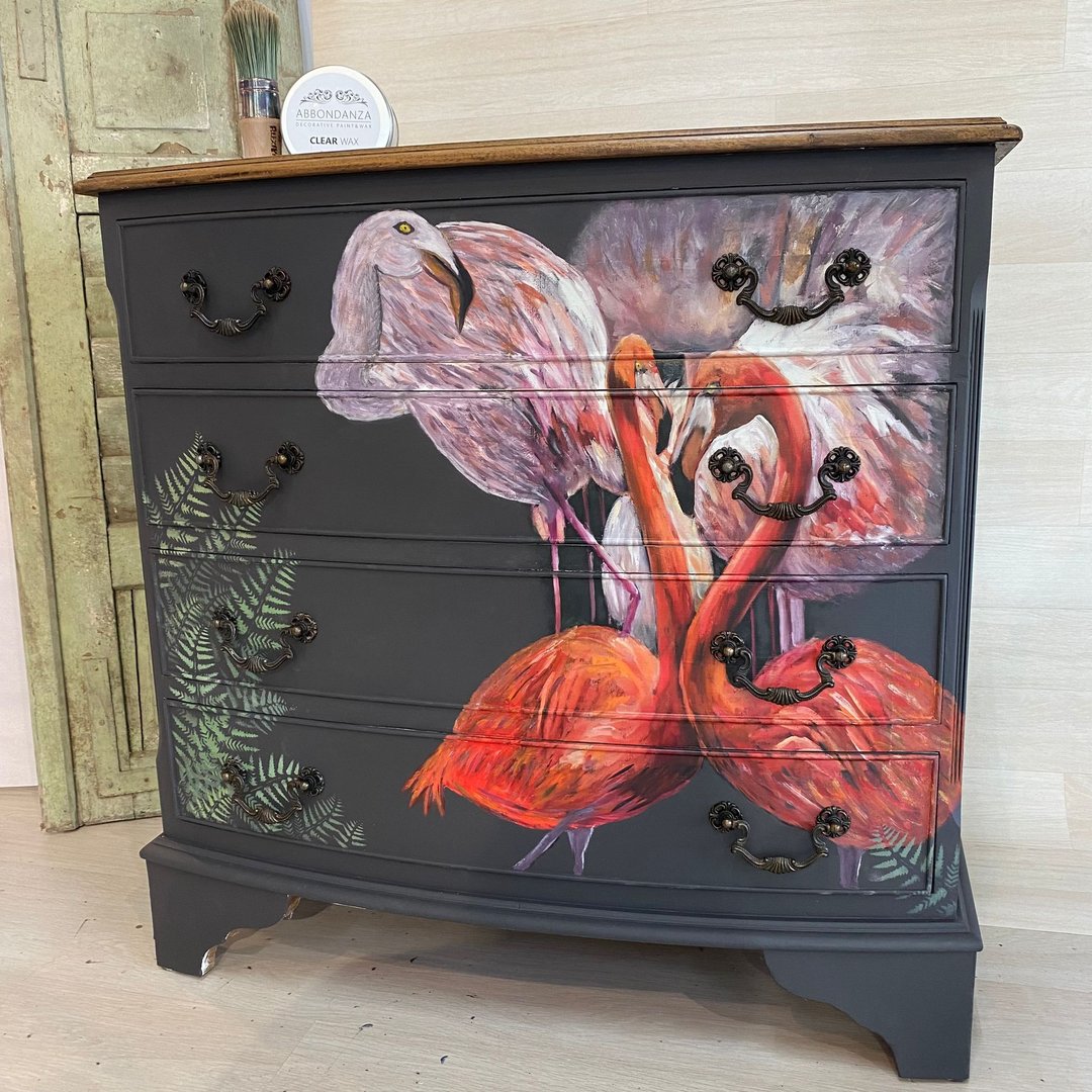 Eine schwarze Kommode mit einem Decoupage Papier das Flamingos zeigt.