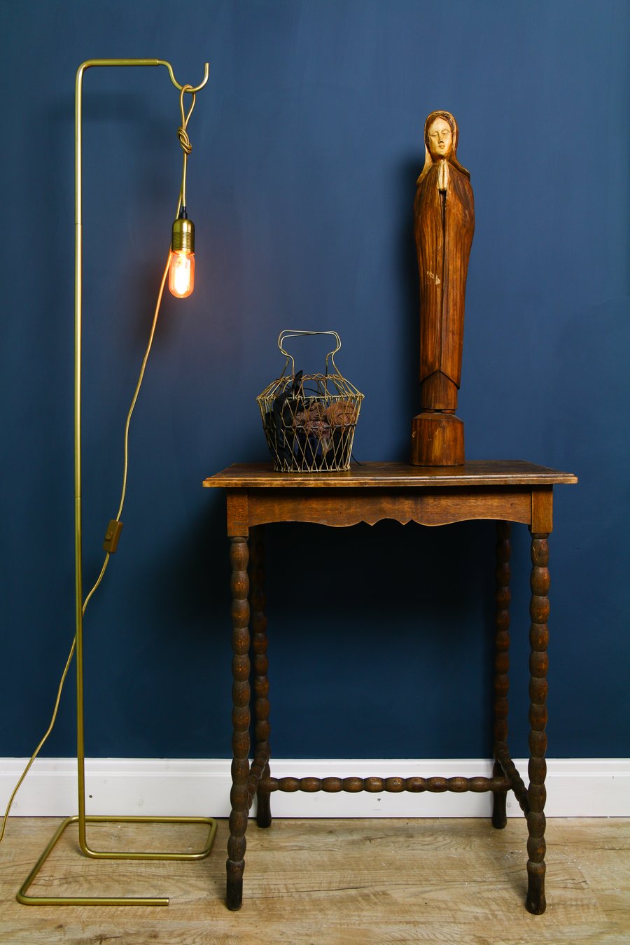 Das Bild zeigt eine dunkelblaue Wand mit einem Tischen und einer Lampe davor.