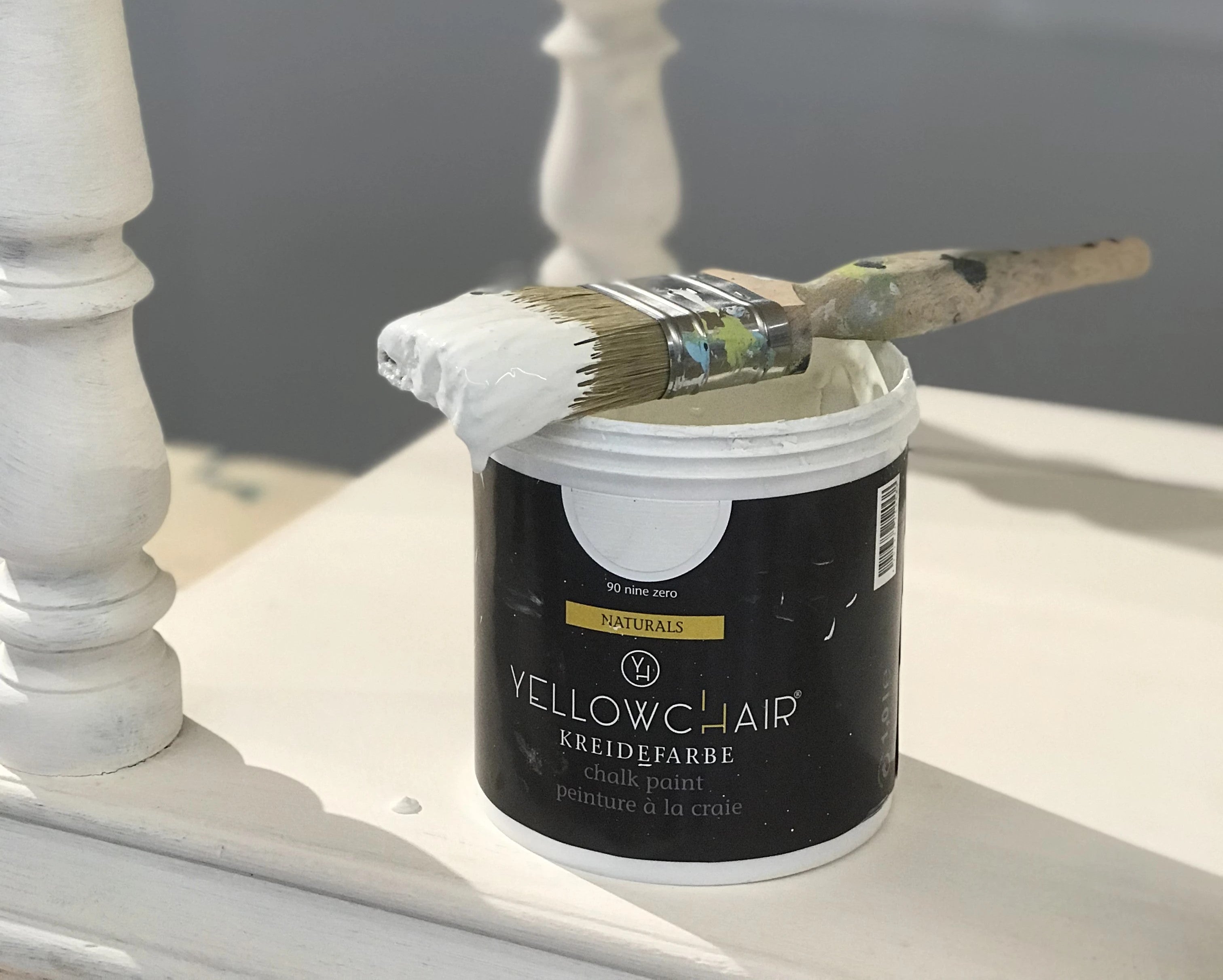 Ein Topf Yellowchair Kreidefarbe mit einem Pinsel voller Farbe